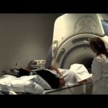 A patient lies on a bed next to an MRI machine.